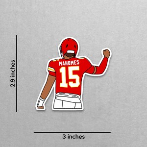 May include: A sticker featuring a cartoon illustration of a football player in a red uniform with the name "Mahomes" and the number "15". The sticker is approximately 3 inches wide and 2.9 inches tall.
