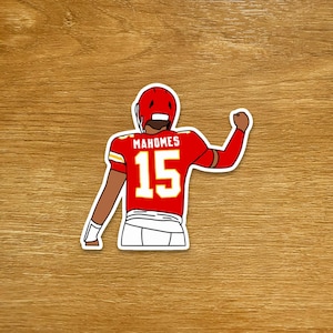 May include: A sticker featuring a cartoon illustration of a football player in a red uniform with the name "Mahomes" and the number "15". The player is wearing a red helmet and white pants, with his fist raised in a celebratory gesture.