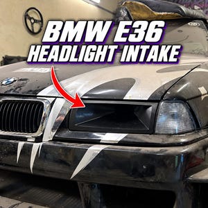 May include: A black BMW E36 headlight intake installed on the front of a black and white car. The text BMW E36 HEADLIGHT INTAKE is displayed above the vehicle, and a red arrow points directly to the matte black air intake component.