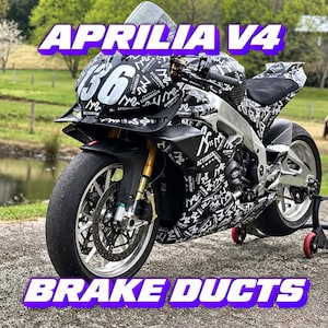 May include: An Aprilia V4 sport motorcycle featuring a black and white patterned wrap with the number 36 on the front fairing. The motorcycle is equipped with brake ducts, gold-coloured front forks, and a black seat, supported by a rear stand.