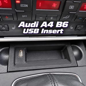 May include: A black, rectangular USB insert designed for an Audi A4 B6 centre console, featuring a single USB port integrated into a textured plastic housing. The text "Audi A4 B6 USB Insert" is overlaid in white and purple on the image.