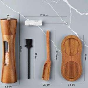 May include: A wooden salt and pepper grinder (20 cm tall, 5.5 cm wide) with a clear viewing window, a cleaning brush (17 cm long), a small black brush (13 cm long), a wooden spoon (17.5 cm long, 2.7 cm wide), and a wooden tray (15 cm tall, 7.8 cm wide).
