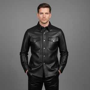 Könnte beinhalten: Ein schwarzes Lederhemd mit zwei Brusttaschen und silberfarbenen Knöpfen. Das Hemd hat einen klassischen Kragen und lange Ärmel. Das Model trägt eine schwarze Lederhose. Ein stilvolles Kleidungsstück.