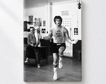 May include: A black and white canvas print featuring a person jumping rope in a gym, wearing a tank top with the text WIN ROCKY WIN and dark shorts. A seated person watches in the background. A sign on the wall reads DO NOT SPIT OR THROW GUM ON THE FLOOR.