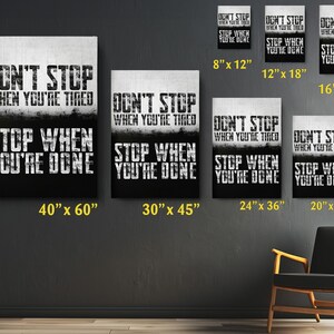 a collection of motivational posters with the text "DON'T STOP WHEN YOU'RE TIRED" displayed on them. The posters vary in size, with some being larger than others, and are arranged on a wall. There is also a chair in the background, suggesting a space for relaxation or contemplation.