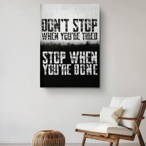 a motivational poster with the text "DON'T STOP WHEN YOU'RE TIRED STOP WHEN YOU'RE DONE" displayed on a wall above a wooden chair.