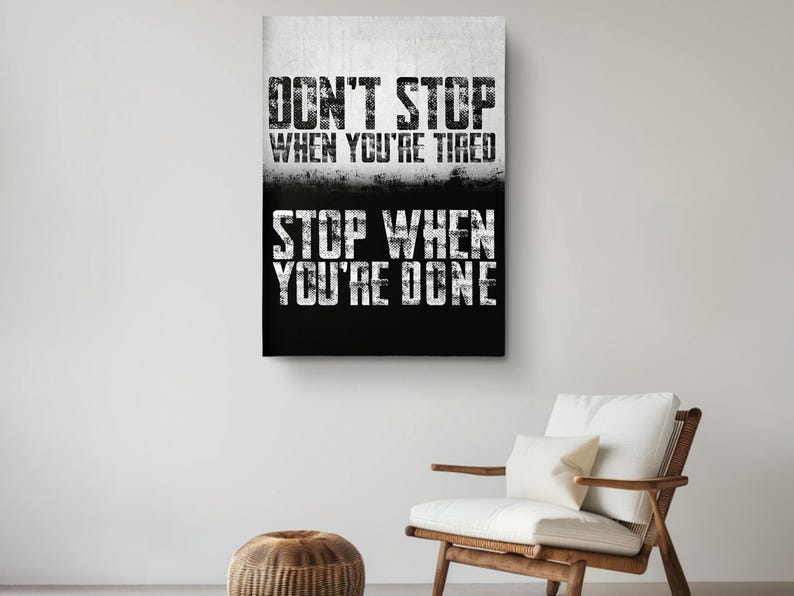 a motivational poster with the text "DON'T STOP WHEN YOU'RE TIRED STOP WHEN YOU'RE DONE" displayed on a wall above a wooden chair.