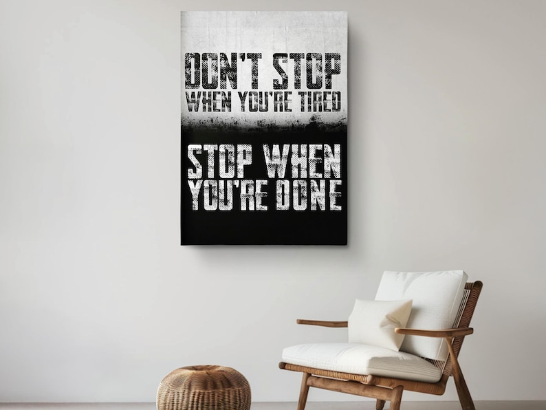 a motivational poster with the text "DON'T STOP WHEN YOU'RE TIRED STOP WHEN YOU'RE DONE" displayed on a wall above a wooden chair.