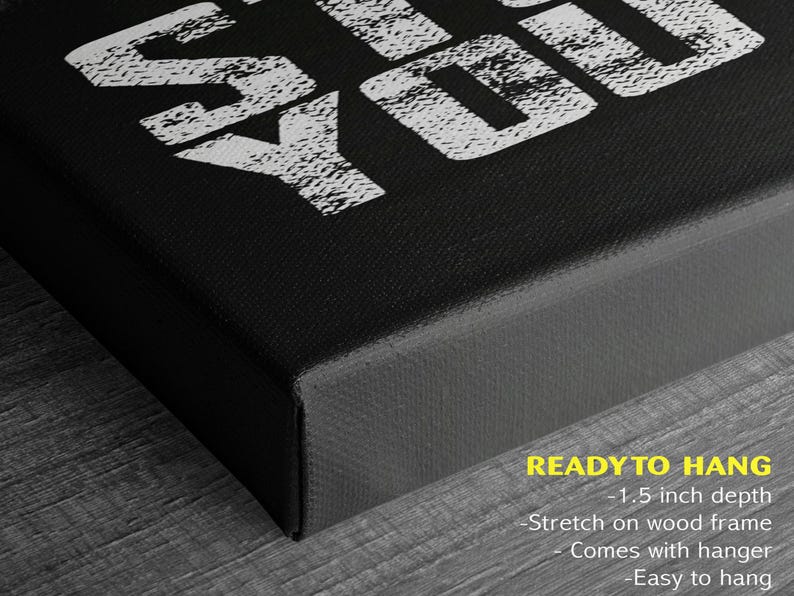 a close-up view of a black canvas or frame with a white text design on it. The text design appears to be a stylized phrase or message, and the image is described as a "ready to hang" piece of art.