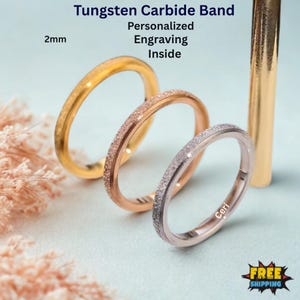 May include: Three tungsten carbide rings in gold, rose gold, and silver, each 2mm wide. The bands have a textured, glittery finish. Text on the image reads "Tungsten Carbide Band, Personalized Engraving Inside". One ring is engraved with the name "Ceri".