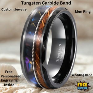 Puede incluir: Un anillo de banda de carburo de tungsteno negro con un diseño facetado. El anillo presenta una incrustación central de madera y material iridiscente, acentuada con una fila de pequeñas piedras de color plateado. El texto "Tungsten Carbide" es visible.