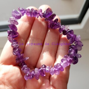 Peut inclure: Un bracelet composé d'éclats d'améthyste violets. Le bracelet est fait de petites pierres d'améthyste de forme irrégulière. Le texte "Le royaume de Cleophe" est visible.