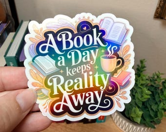 Puede incluir: Una pegatina colorida con el texto "A Book a Day keeps Reality Away". El diseño incluye ilustraciones de libros, una taza de café y elementos decorativos en tonos azules, naranjas y morados.