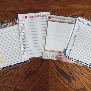 May include: Four white notepads with lined pages and various designs. Two pads say "Teacher Life" with apple and pencil graphics. One says "Teaching is a work of" and another says "Teach, Love, Inspire".