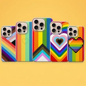 Puede incluir: Una colección de cinco fundas para teléfonos con coloridos diseños de arcoíris. Cada funda presenta un patrón diferente, incluyendo rayas, corazones y corazones pixelados, todos en vibrantes colores del arcoíris. Las fundas se muestran sobre un fondo amarillo.