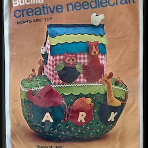 May include: A Bucilla creative needlecraft kit to make a Noah's Ark toy. The kit includes felt fabric, cotton floss, and instructions to create a 14-inch tall ark with 10 animal figures. The kit is labeled "Noah's Ark" Toy and "Stands 14" High".