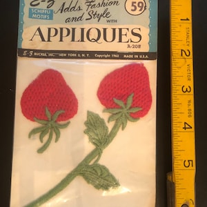 May include: A package of two red embroidered strawberry appliques with green leaves and stems. The package is labeled "E-3 Adds Fashion and Style with Appliques" and "A-208".