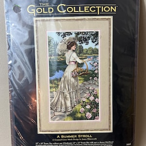May include: A cross-stitch kit from The Gold Collection, featuring a detailed image of a woman in a white dress strolling by a lake. The kit includes thread, fabric, and instructions. Frame size without mat is 10" x 18" (25x46cm).