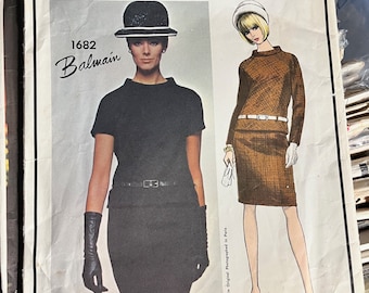 May include: Vogue Paris Original sewing pattern number 1682 for a Balmain design. The pattern features two illustrations of women wearing dresses. One woman is wearing a black dress with a black hat and the other is wearing a brown dress with a white hat.