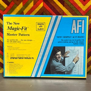 May include: A vintage "Magic-Fit" Master Pattern box with text and a photo of a man. The box is yellow and blue with text that reads "Designing with Dusan" and "American Fashion Institute, Inc."