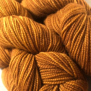May include: Close-up of a skein of brown and beige yarn. The yarn is soft and fluffy, and it has a subtle sheen.