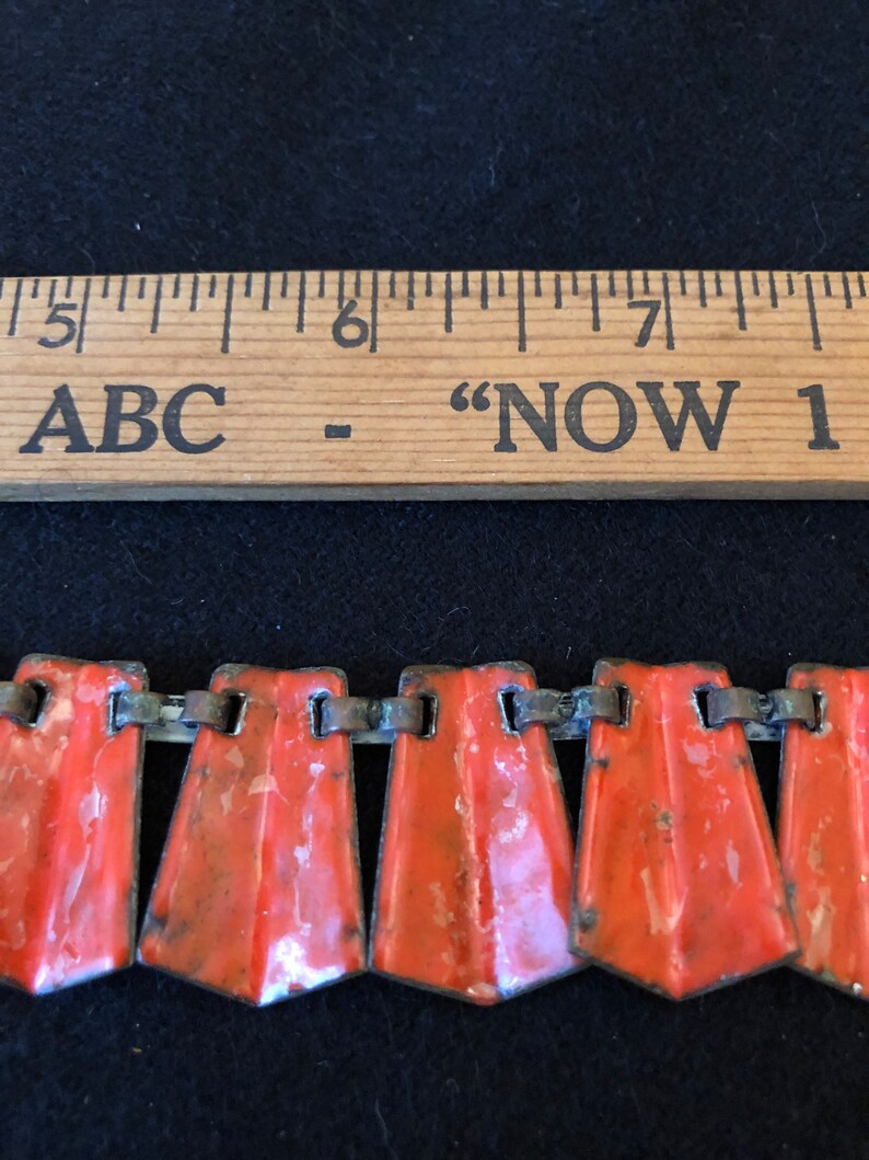 May include: A close-up of a red and silver metal chain necklace. The necklace is made up of a series of small, rectangular, red enamel pieces connected by silver metal links. The necklace is about 6 inches long.