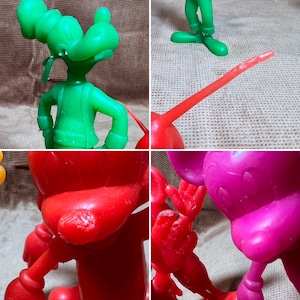 May include: A set of four vintage plastic cartoon character figurines. The figurines are green, red, pink, and yellow. The figurines are of Mickey Mouse, Donald Duck, Goofy, and Pluto.