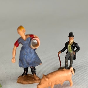 May include: Miniature figurines of a farmer, a gentleman, and a pig. The farmer wears a blue dress and red sleeves, holding a bucket. The gentleman is in a black coat and top hat, with a cane. The pig is light pink.