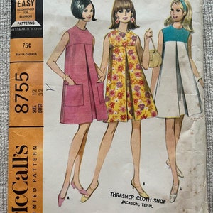 May include: Vintage McCall's printed sewing pattern, featuring illustrations of three dresses. The pattern includes a pink dress with pockets, a floral dress, and a white dress with a blue top. The pattern is labeled "Easy to Sew."