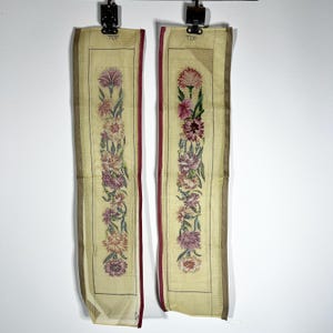 May include: Two vertical rectangular needlepoint canvases featuring a central floral pattern of carnations in shades of pink, purple, and green on a cream background. Each canvas has a dark red border, a black line frame, and the word TOP printed.