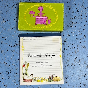 May include: A rectangular lime green box with the text Here's What's Cookin' and a magenta illustration of a stove, paired with a notepad titled Favorite Recipes featuring 25 recipe cards, a chicken, kitchen utensils, and floral accents.