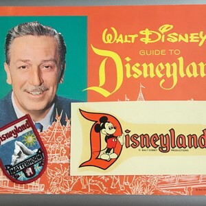 Puede incluir: Una gu&iacute;a vintage de Disneyland con un parche de Disneyland rojo, blanco y azul, una pegatina de Disneyland amarilla y blanca y una foto de Walt Disney.