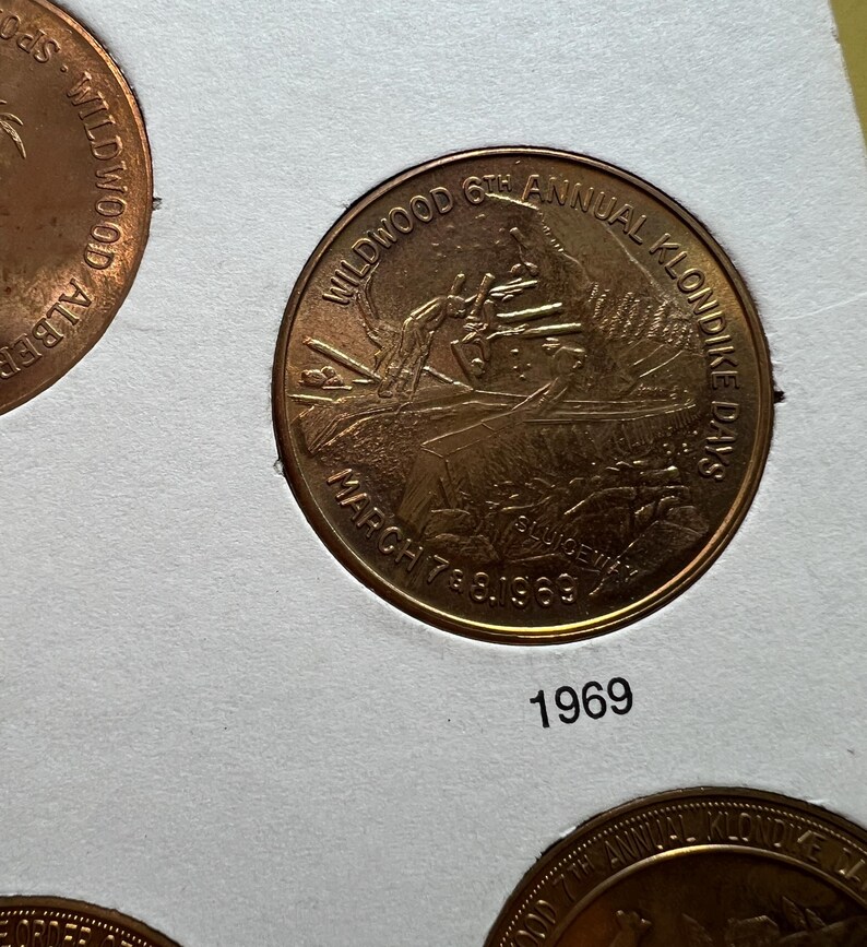 May include: A bronze coin from the Wildwood 6th Annual Klondike Days, dated March 7 & 8, 1969. The coin features an image of a person and text that reads "Wildwood 6th Annual Klondike Days" and "March 7 & 8, 1969". The year "1969" is printed below the coin.