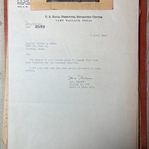 May include: A vintage document from the U.S. Naval Personnel Separation Center, Camp Wallace, Texas, dated April 5, 1946. The document is a letter with text, a serial number, and a name. The document is in a red folder.