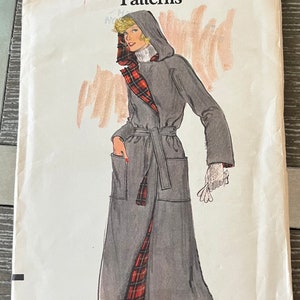 May include: Vintage sewing pattern for a gray coat with a red and black plaid lining. The pattern is for size 12 and is from Very Easy Vogue Patterns. The pattern is titled "Very Easy Vogue Patterns" and has the number 9312 printed on it.