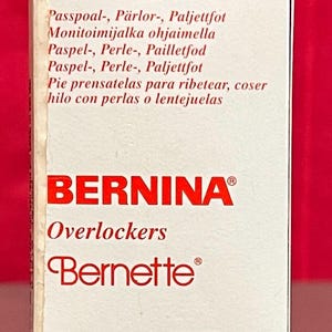 May include: A white box with red trim and the text "BERNINA Overlockers Bernette® A92017760C0A". The box also has text in Finnish and Spanish.