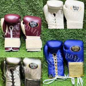 Könnte beinhalten: Eine Sammlung von Boxhandschuhen in verschiedenen Farben wie Kastanienbraun, Weiß, Blau und Silber. Jedes Paar verfügt über ein Schnürsystem und ein auffälliges ovales Logo-Emblem am Handgelenk mit der Aufschrift No Boxing No Life.