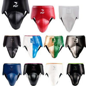 May include: A selection of protective athletic cups in various colours, including black, red, white, blue, and gold. Each cup features the "FLY" logo and is designed for sports like boxing and martial arts.