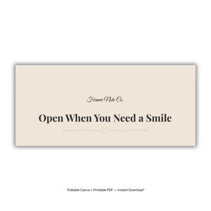 Peut inclure: Une carte rectangulaire crème avec le texte "Open When You Need a Smile" en police serif. La carte porte les mots "Forever Note Co." en police script en haut. Une ligne décorative avec un cœur est en dessous du texte principal.