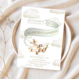 以下が含まれることがあります： 水彩デザインの誕生日招待状。招待状には木製の飛行機、雲、そして「3rd Birthday Expedition」というテキストが描かれています。招待状は白い背景にあります。