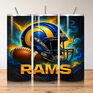 May include: A tumbler featuring a blue and yellow football helmet and a brown football. The word "RAMS" is displayed in gold lettering. The background has blue and yellow abstract designs.