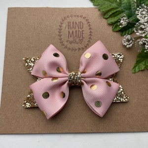 Peut inclure: Un n&oelig;ud rose et or &agrave; pois avec des accents de paillettes. Le n&oelig;ud est fait &agrave; la main et porte une &eacute;tiquette qui dit "Hand Made with love".