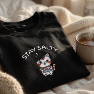 Maglietta ricamata con gatto "Stay Salty Tinned Sardines"