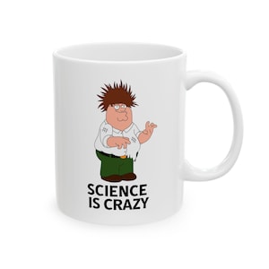May include: White ceramic mug featuring a cartoon character with spiky brown hair, glasses, and a white shirt. The character is wearing green pants and the text "SCIENCE IS CRAZY" is printed below the character.