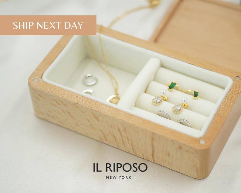 Puede incluir: Caja de joyer&iacute;a de madera con interior blanco, que contiene varios pendientes, anillos y un collar. Los pendientes son de oro y plata con piedras preciosas y perlas. La caja tiene el texto "IL RIPOSO NEW YORK".
