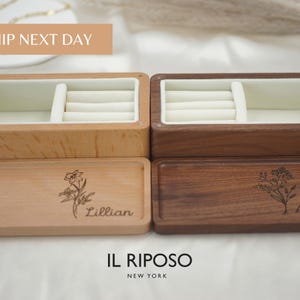 Puede incluir: Dos joyeros de madera, uno claro y otro oscuro, con interiores color crema. Las tapas est&aacute;n grabadas con dise&ntilde;os florales y nombres. El texto "IL RIPOSO NEW YORK" est&aacute; en la parte inferior.