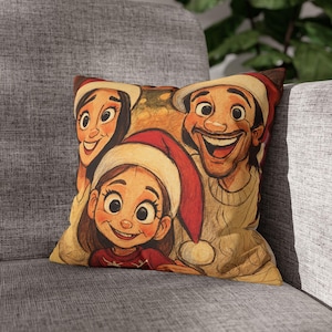 May include: Square decorative pillow featuring a cartoon illustration of a family wearing Santa hats. The artwork depicts a smiling woman, a child, and a man, all with joyful expressions. The pillow is placed on a gray sofa.