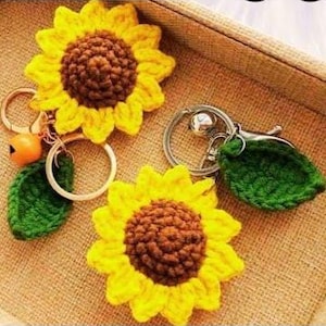 Puede incluir: Llaveros de girasol tejidos a crochet con pétalos amarillos y centros marrones. Cada llavero incluye una hoja verde y un anillo de metal.