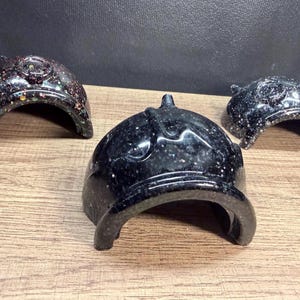 May include: Three semi-circular, dome-shaped resin structures in black with embedded glitter. The central piece features a smooth, dark finish with fine white speckles, while the two flanking pieces display a darker base with multi-colored glitter.