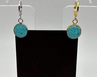 Puede incluir: Pendientes con piedras circulares de color turquesa. Uno tiene un aro plateado y el otro dorado. Se exhiben en una tarjeta negra con el texto "MIDNIGHT TIMBER CO."